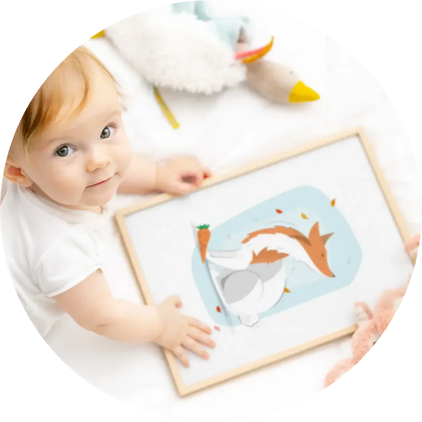 Un bébé touche une affiche Pipattes encadrée, posée au sol.